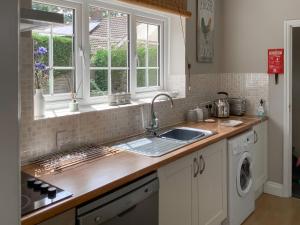 a kitchen with a sink and a washing machine at Clinton Cottage in Yaxham