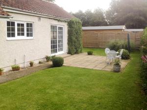 a garden with a bench in the middle of a yard at Clinton Cottage in Yaxham