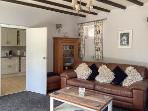 a living room with a brown couch and a table at Clinton Cottage in Yaxham