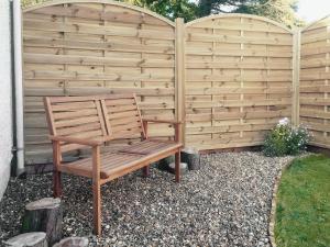 a wooden bench sitting in front of a fence at Clinton Cottage in Yaxham +7 photos