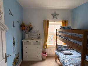 a bedroom with a bed and a dresser and a window at Hideaway Cottage in Hunstanton