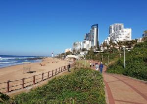 a beach with people walking on the sand and buildings at 1 Seabreeze Cottage in Durban
