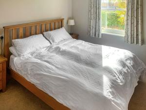 a bed with a white comforter and a window at 1 Lonsdale House in Keswick +6 photos