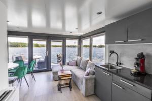a kitchen and living room with a couch and a table at Houseboat Marina Mookerplas with XL Hot Tub | 4 - 6 people in Middelaar