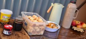a table with a container of food and a bowl of fruit at Home Comfort in Poconé