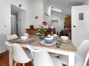 a dining room table with chairs and a vase of flowers at Gara Mill Cottage in Kingsbridge