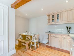 a kitchen with white cabinets and a table and chairs at The Stirrup Cottage in Blyborough