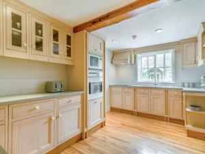 a large kitchen with wooden cabinets and a window at The Stirrup Cottage in Blyborough
