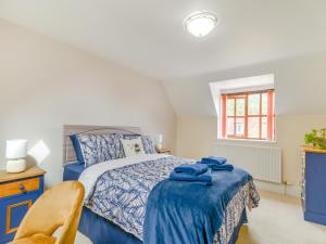 a bedroom with a blue bed and a window at The Stirrup Cottage in Blyborough +8 photos