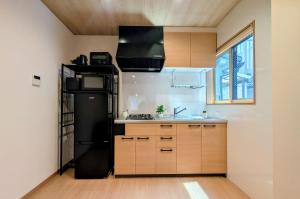 a kitchen with a black refrigerator and wooden cabinets at Dream Stays HIKARI in Osaka
