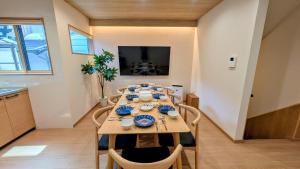 a dining room with a table with chairs and a television at Dream Stays HIKARI in Osaka
