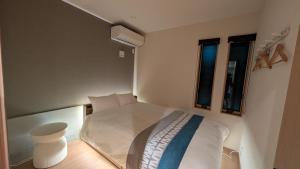 a small bedroom with a white bed and two windows at Dream Stays HIKARI in Osaka +49 photos