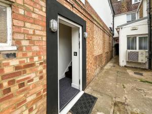 an open door to a brick building with a door at Whitstable May House in Whitstable