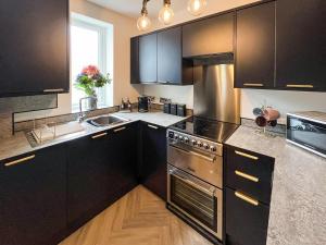 a kitchen with black cabinets and stainless steel appliances at Whitstable May House in Whitstable +9 photos
