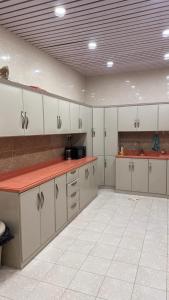a large kitchen with white cabinets and red counter tops at شقق رواق in Abha +14 photos
