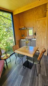 a dining room with a wooden table and a kitchen at Tiny House De Skries in Westergeest