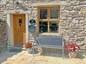 a bench in front of a building with a door at Quarry Cottage in Barnoldswick