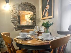 a dining room table with chairs and a table with wine glasses at Quarry Cottage in Barnoldswick