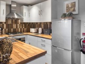 a kitchen with white cabinets and a stainless steel refrigerator at Quarry Cottage in Barnoldswick +11 photos