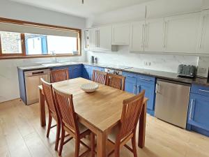 a kitchen with a wooden table and blue cabinets at Broadsea Cottage in Fraserburgh