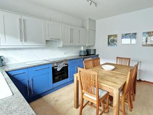 a kitchen with a wooden table and blue cabinets at Broadsea Cottage in Fraserburgh