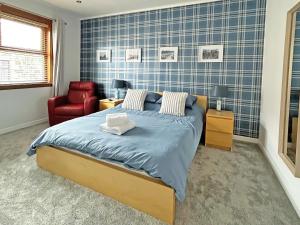 a bedroom with a bed and a red chair at Broadsea Cottage in Fraserburgh