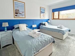 a bedroom with two beds and a blue wall at Broadsea Cottage in Fraserburgh
