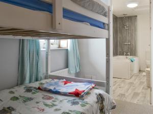 a bedroom with a bunk bed and a bathroom at Holemoor Cottage in Bridgerule