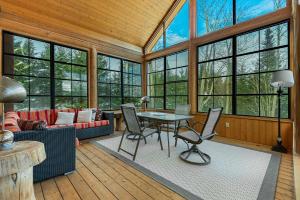a living room with a table and chairs and windows at Spa Pool & Sauna - Laurentides Serenity in Mille-Isles