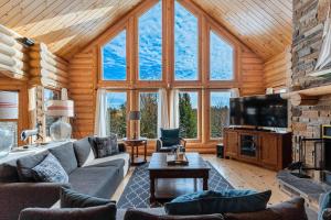 a living room with couches and a television in a cabin at Spa Pool & Sauna - Laurentides Serenity in Mille-Isles +37 photos