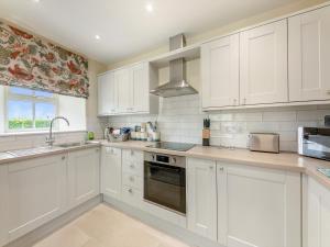 a white kitchen with white cabinets and a window at Nightfold - Uk49890 in Preston +14 photos