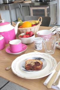 a table with a piece of cake and a bowl of fruit at Demeure Les ragottières in Le Plessis
