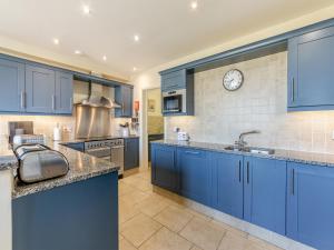 a kitchen with blue cabinets and a clock on the wall at Carriage House - Uk49288 in Preston