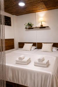 a bed with white towels on it with a lamp at Feliz Puerta - Entire House with Rooftop Terrace, Iquitos in Iquitos