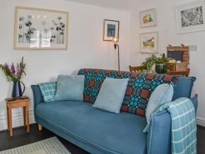 a living room with a blue couch with a blanket at Tan Bryn - Uk44151 in Llanallgo