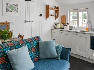 a living room with a blue couch and a kitchen at Tan Bryn - Uk44151 in Llanallgo
