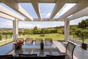a patio with a table and chairs and a view of a field at Sani Invictus Villa in Sani Beach