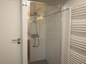 a shower with a glass door in a bathroom at La Chaumière in Flancourt-Catelon