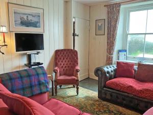 a living room with a couch and a chair at Downhouse Cottage in Treknow