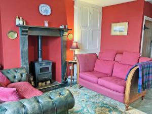 a living room with a couch and a stove at Downhouse Cottage in Treknow