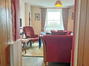 a living room with a red couch and a window at Downhouse Cottage in Treknow