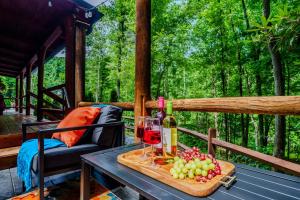 a table with a bottle of wine and grapes on a porch at Peaceful Luxury in the Smokey Mountains w Hot Tub and Pet Friendly Cabin B in Elizabethton