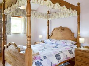 a bedroom with a wooden bed with a canopy at Meadow View - Iom in Brandesburton