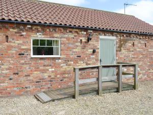 a brick building with a window and a wooden deck at Meadow View - Iom in Brandesburton +13 photos