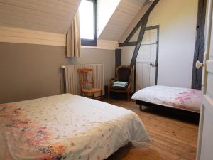 a bedroom with a bed and a chair and a window at La longère in Flancourt-Catelon