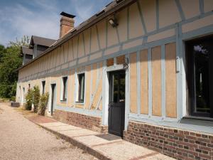 a building with a black door on the side of it at La longère in Flancourt-Catelon