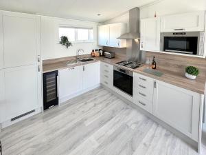 a kitchen with white cabinets and a wooden floor at St Mabyn Lodge Escape in Bodmin