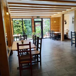ein Esszimmer mit Tisch, Stühlen und Fenstern in der Unterkunft Cabana CODRIN in Rausor