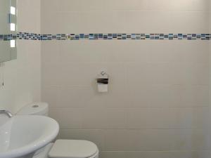 a white bathroom with a toilet and a sink at Barleycorn in Holwell