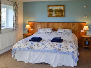 a bedroom with a bed with two blue pillows on it at Barleycorn in Holwell